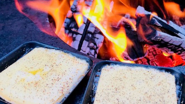 Raclette-Pfändli mit gewürztem Käse schmelzen auf der Grillfläche des swissfirecube garden